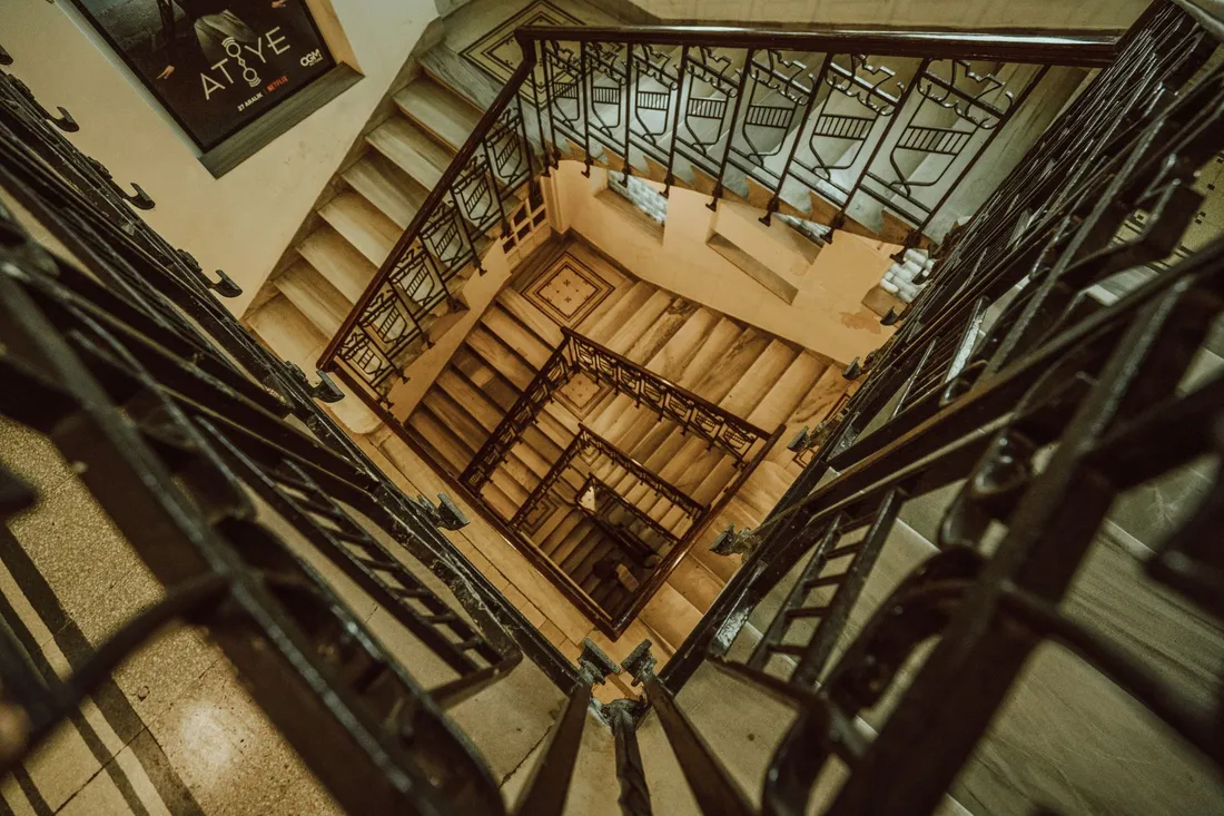 Elegantes Altbau-Treppenhaus mit geschwungenem Geländer und hohen Decken